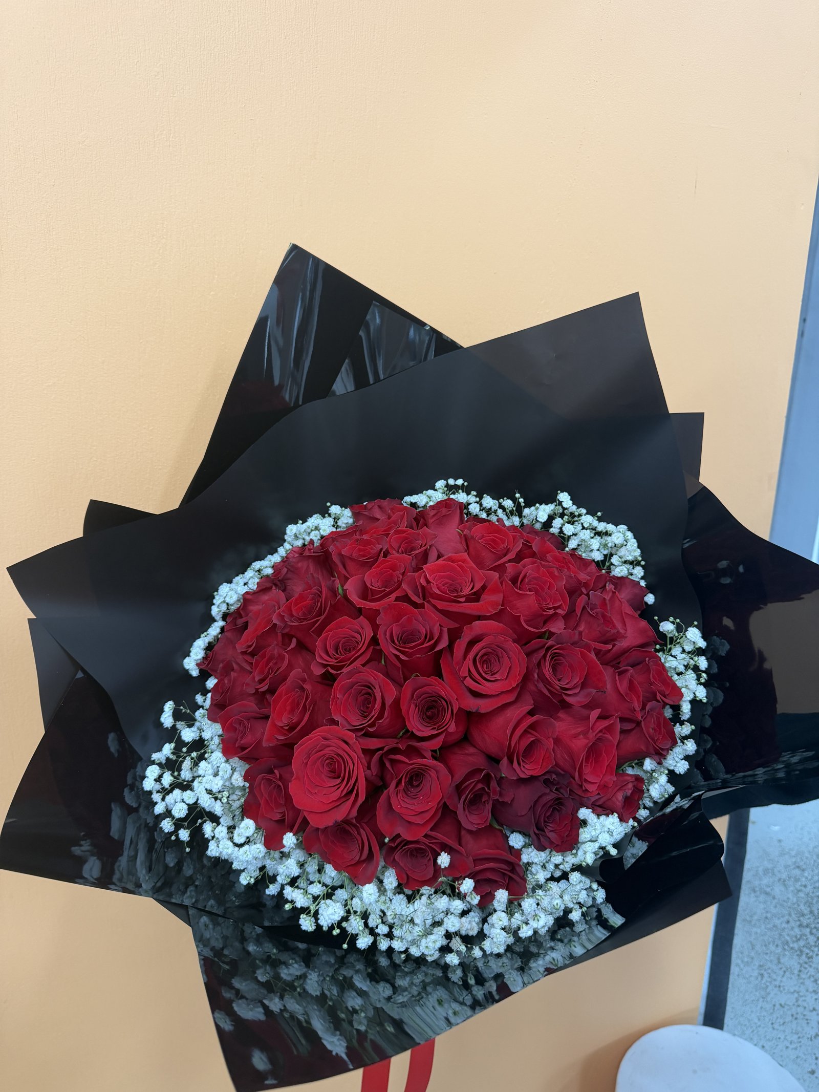 Large bouquet of red roses edged with baby's breath in black wrapping