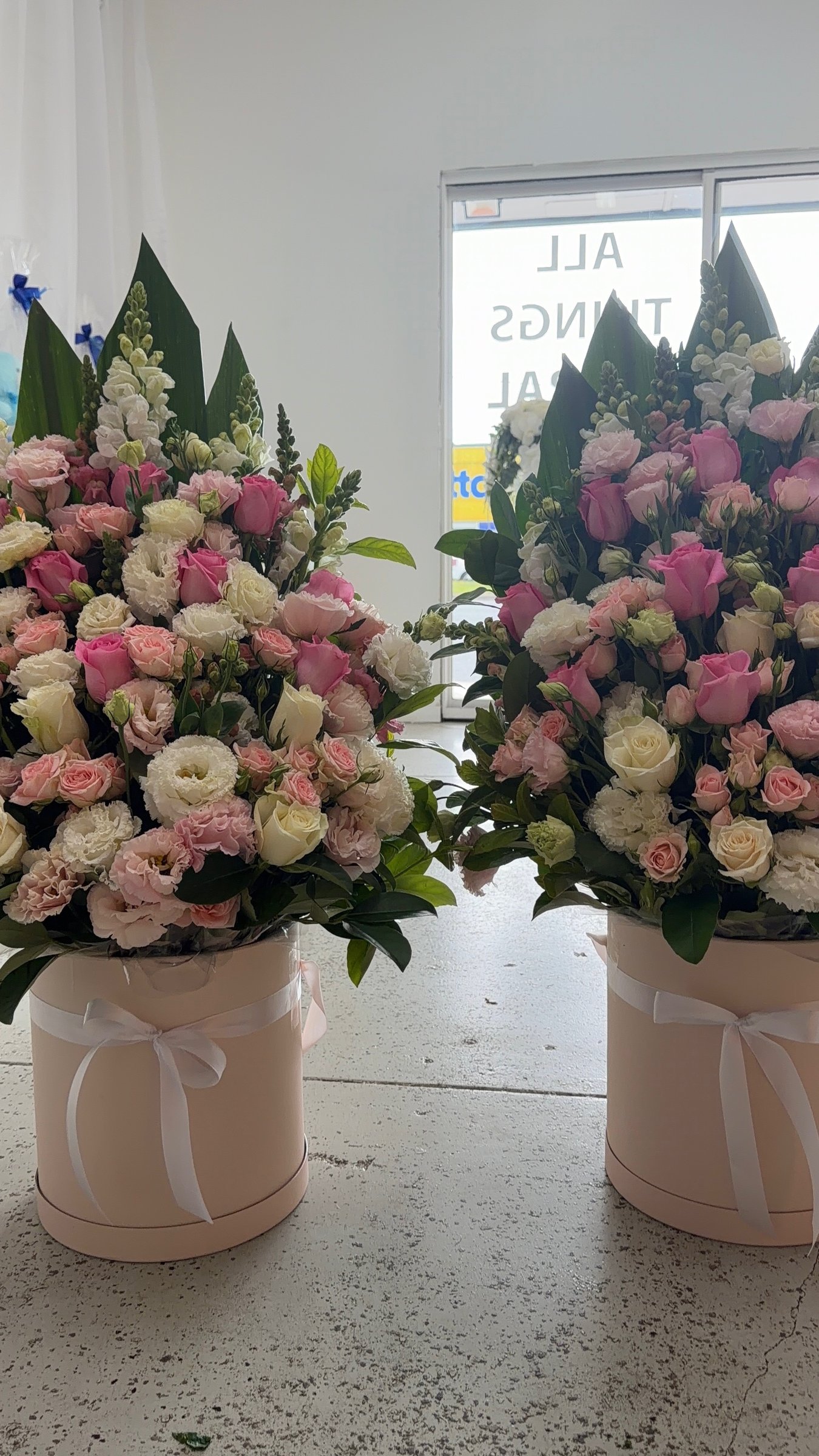 Pink and cream rose arrangements in round hat boxes tied with ribbon