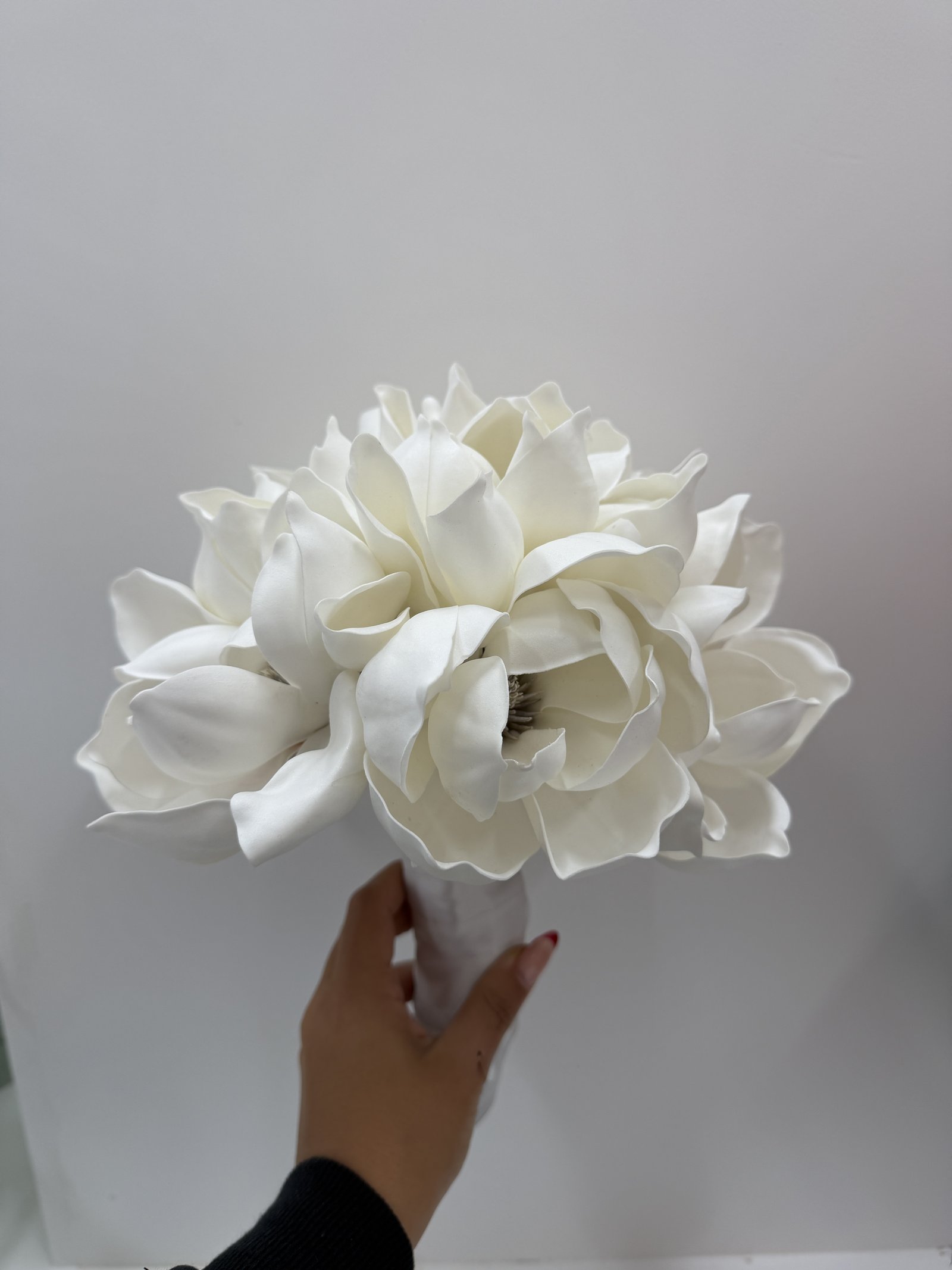 Hand holding a white magnolia bridal bouquet