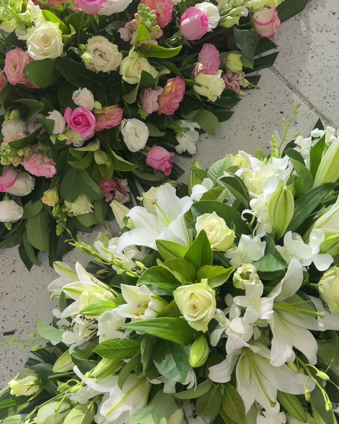 Two casket sprays — pink and white roses, and white lilies with roses