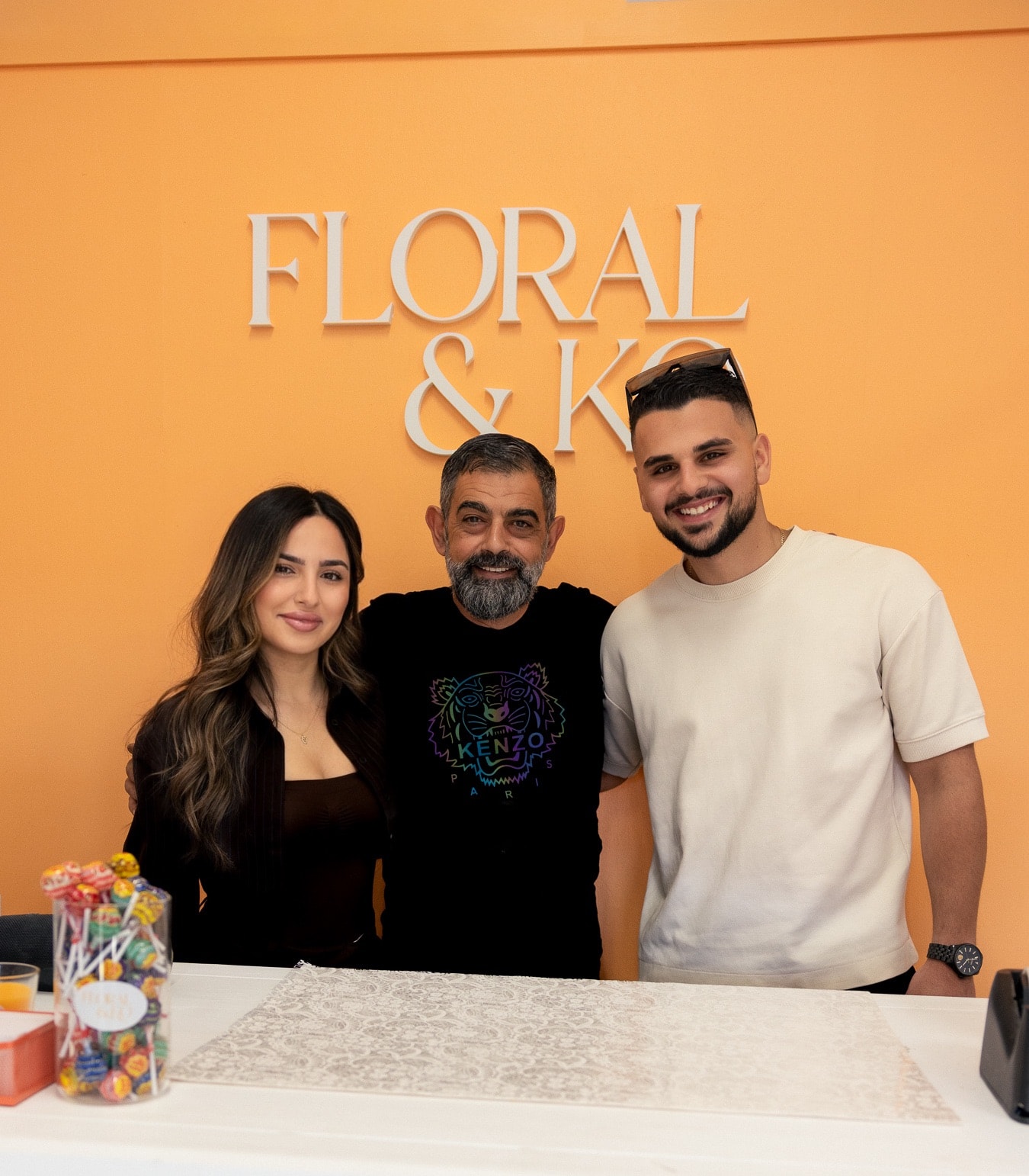 The Floral & Ko family standing together behind the shop counter, beneath the Floral & Ko sign