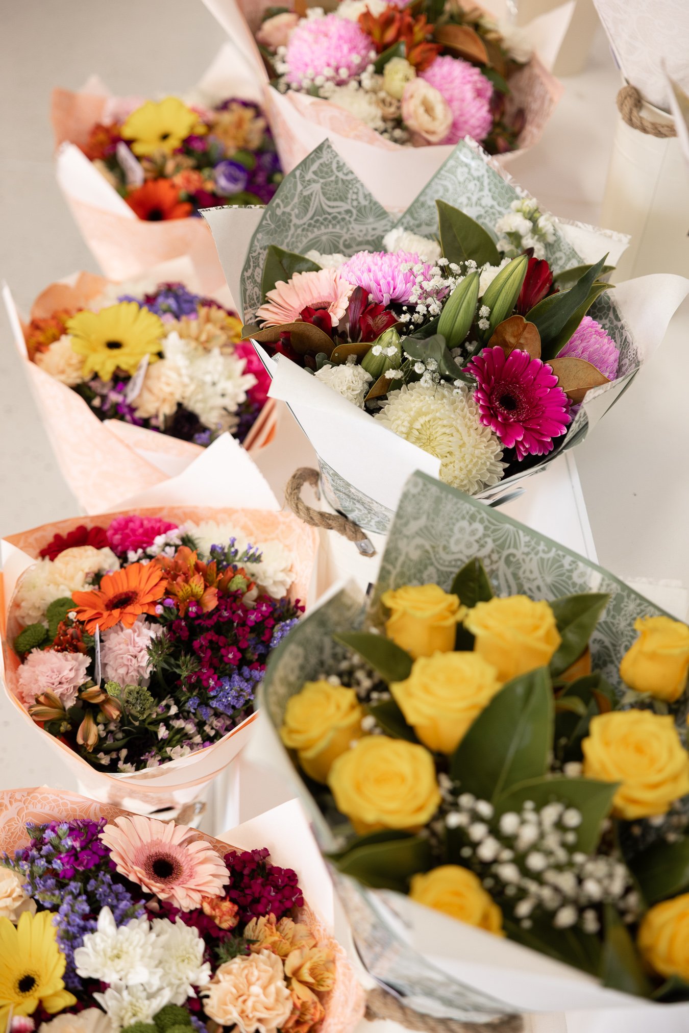 Wrapped seasonal bouquets in mixed colours — gerberas, roses and chrysanthemums